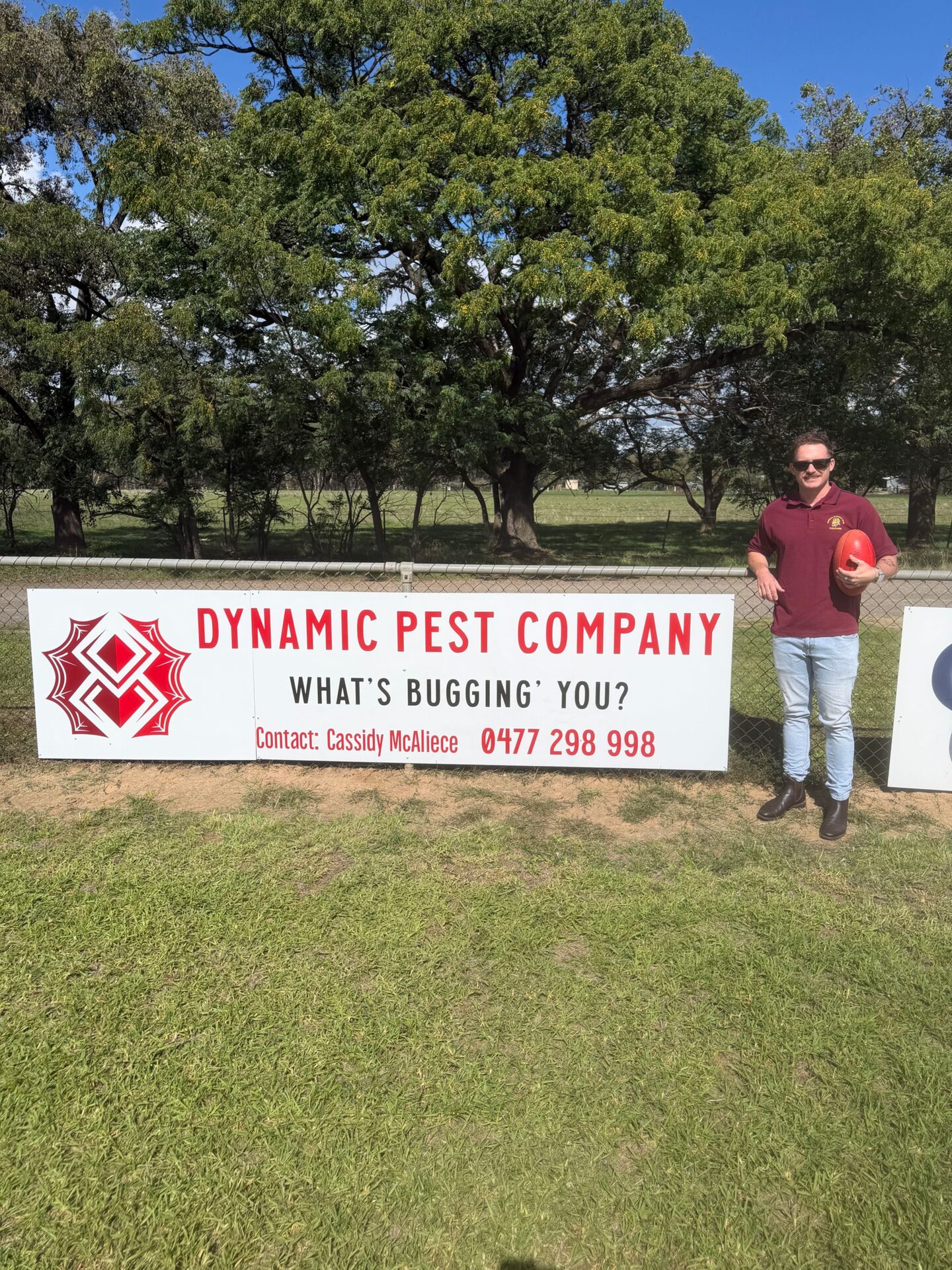 Cassidy McAleece, owner of Dynamic Pest Company, beside the company sign